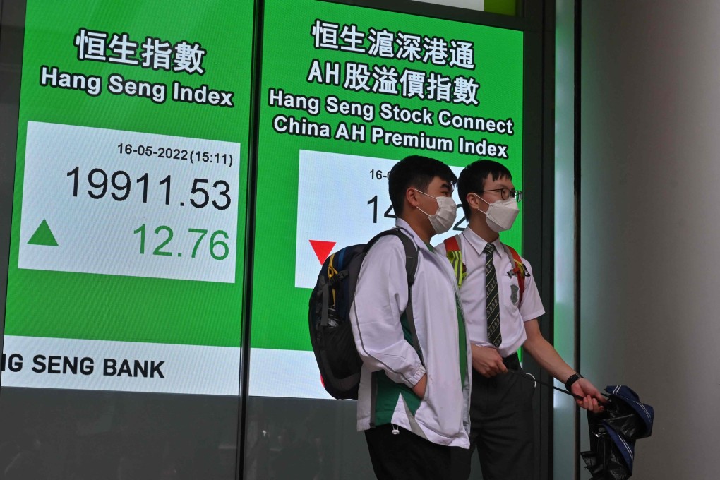 Students stand next to a bilingual display of the Hang Seng Index. With China and the United States reaching a landmark audit deal, Hong Kong is expected to host the audits. There will be a lot of opportunities for bilingual people. Photo: AFP