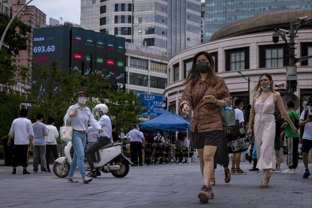 People walk in front of the jumbo screen showing the latest economic and stock updates in Shanghai on June 23. Photo: EPA-EFE