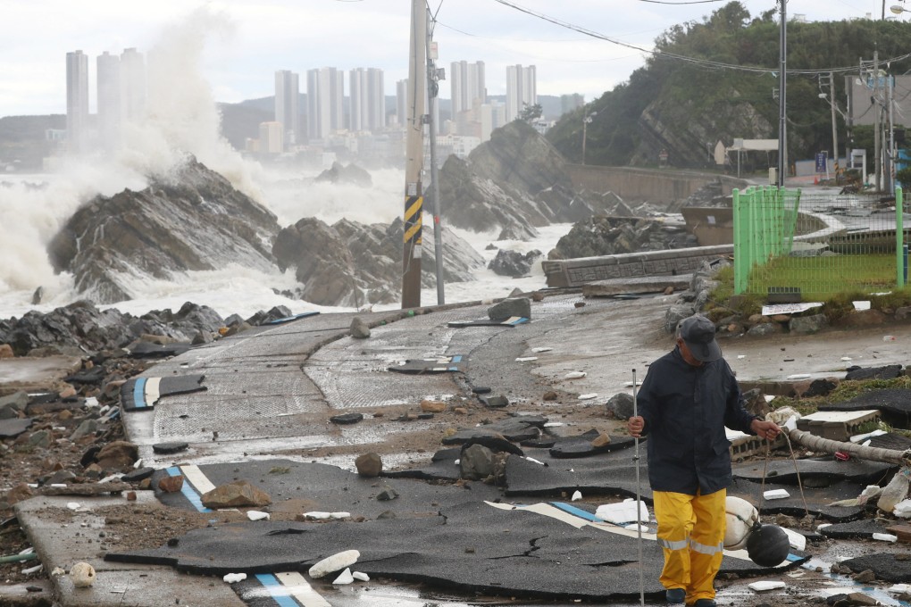 A man walks on a road damaged by Typhoon Hinnamnor along the coast in Ulsan, South Korea, on Tuesday. Photo: Yonhap via Reuters