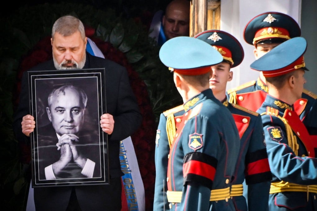 Honour guards stand by a man holding a photograph of the late Soviet leader Mikhail Gorbachev, as his coffin is brought out after a memorial service at the Pillar Hall of the House of the Unions on September 3. Russian President Vladimir Putin did not attend the funeral. Photo: AFP