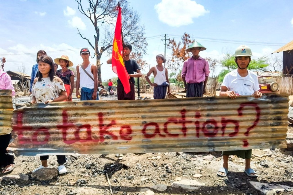 Protesters hold a sign reading ‘How many dead bodies does UN need to take action?’ written on the remains of a roof scavenged from a village burned down by junta forces in Myanmar. Photo: Aung Khant Zaw via Reuters