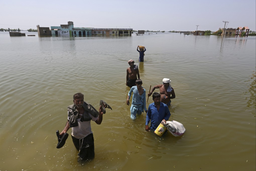 Victims of flooding carry belongings salvaged from their homes in Pakistan on Thursday. The deluge, which began in mid-June, has triggered landslides and collapsed houses, killing over 1,350 people including hundreds of children, and leaving more than 600,000 homeless. Photo: AP