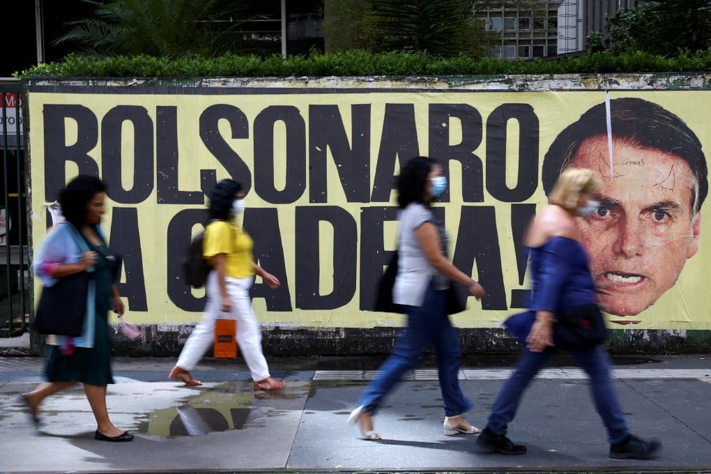 People walk past a poster depicting Brazil’s President Jair Bolsonaro with the phrase “Bolsonaro in jail” in Sao Paulo in January. Photo: Reuters