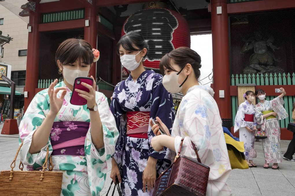 Tourists clad in traditional Japanese dress take pictures in front of the Kaminarimon gate of Sensoji temple in Asakusa, downtown Tokyo, last week. Photo: EPA-EFE