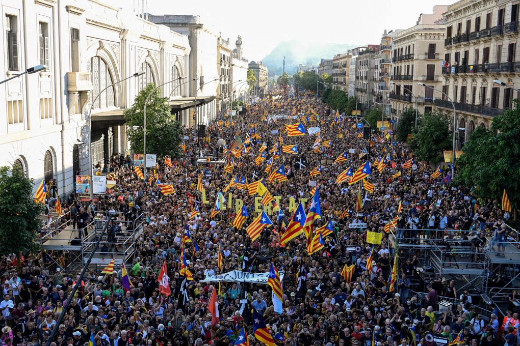 Protesters hold signs reading “Freedom” and wave Catalan pro-independence “estelada” flags during a protest marking the “Diada”, the national day of Catalonia, in Barcelona, Spain on Sunday. Photo: AFP