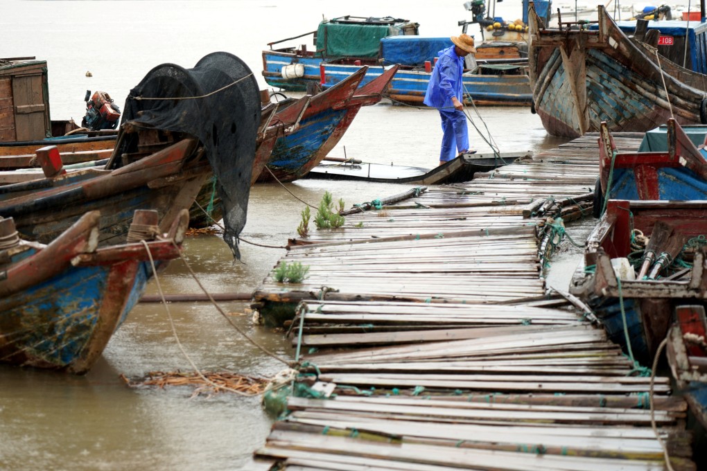 A man ties a boat to a pier as Typhoon Muifa approaches at Yueqing Bay in Wenzhou, Zhejiang province, on Tuesday. Photo: China Daily via Reuters