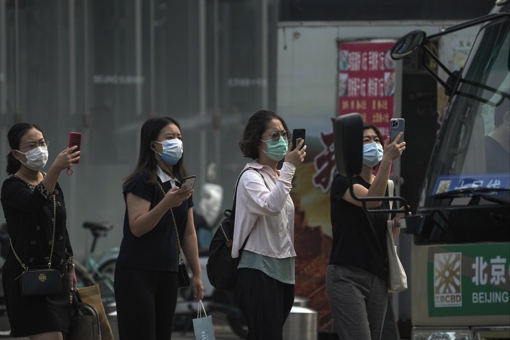 Commuters use their phones to scan health codes before boarding a bus in Beijing on Tuesday. Photo: AP