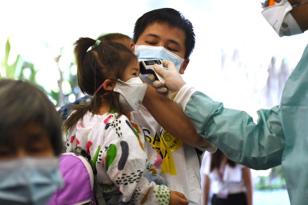 A worker takes the body temperature of a child in Singapore. File photo: Xinhua