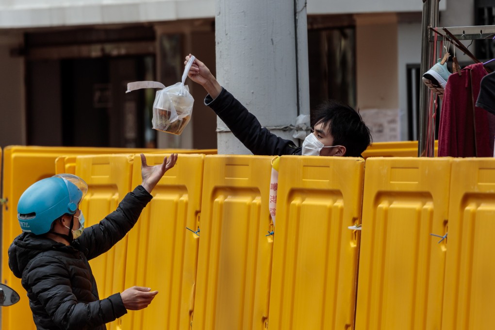 A delivery man passes food over the fence to a resident in quarantine in Shanghai, China, 28 March 2022. Photo: EPA-EFE