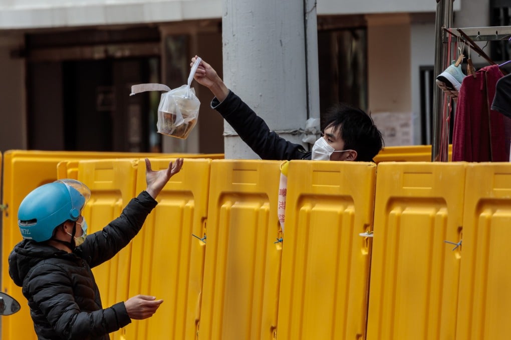 A delivery man passes food over the fence to a resident in quarantine in Shanghai, China, 28 March 2022. Photo: EPA-EFE