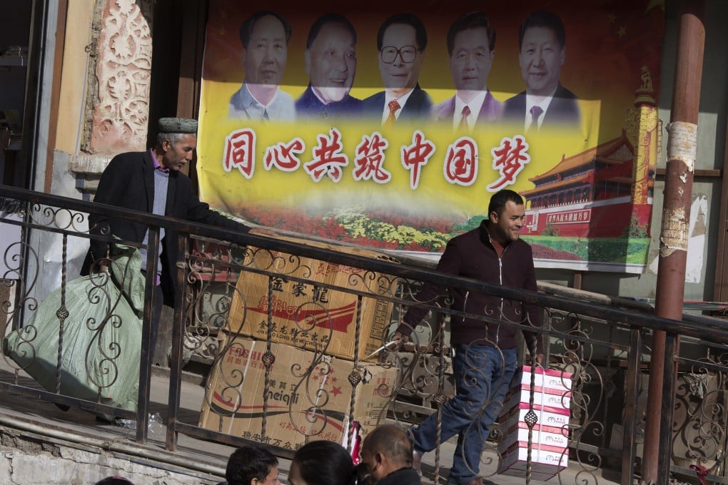 Men transport goods past a mural depicting Chinese leaders in Hotan, Xinjiang Uygur autonomous region, where Beijing has been accused of human rights abuses involving members of Muslim groups. Photo: AP