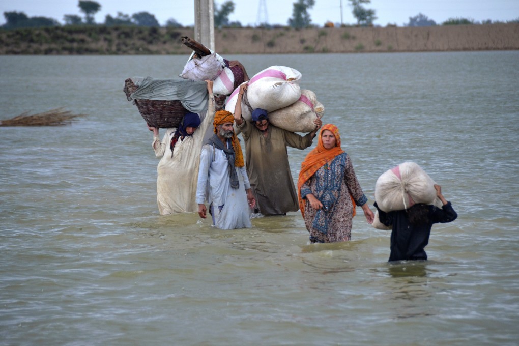 A displaced family wades through a flooded area after heavy rainfall in August 2022, in Jaffarabad, a district of Pakistan’s southwestern Baluchistan province. Photo: AP