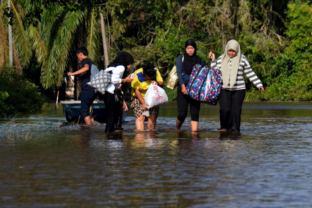 Residents walk in a flooded street in Pahang on their way to a temporary evacuation centre in December 2021. Photo: Bernama/dpa