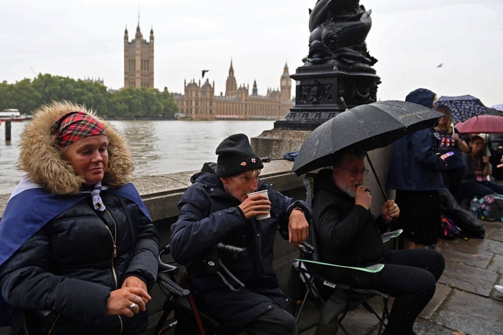 People queue in the rain along the south bank of the River Thames, opposite the Palace of Westminster, home to Westminster Hall and the Houses of Parliament, in London on September 13, as they wait to pay their respects during Queen Elizabeth’s lying in state. Photo: AFP