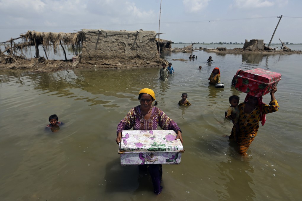 Women carry belongings salvaged from their flooded home after monsoon rains in the Qambar Shahdadkot district of Sindh province in Pakistan on September 6. Photo: AP