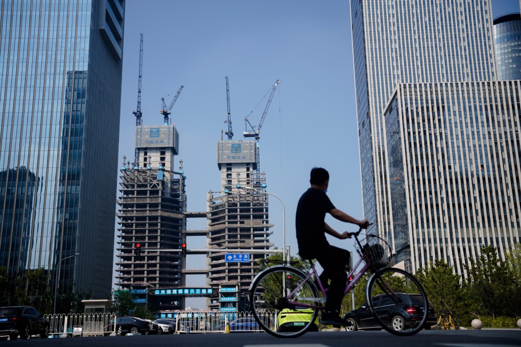 A man rides a bike past residential buildings under construction in Beijing on September 15. Property demand has slumped alongside the rate of marriages as more men are unable to take on the crippling financial responsibility of providing a matrimonial home. Photo: EPA-EFE