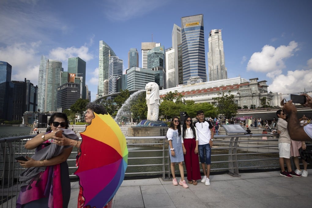 People pose for photos at the Merlion Park in Singapore on August 24. With its latest easing of Covid-19 restrictions, the Hong Kong government is finally showing it is willing to keep up with cities like Singapore. Photo: EPA-EFE