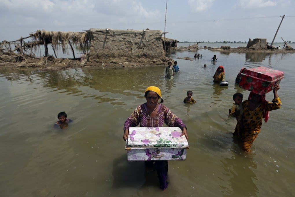 Pakistani women carry belongings salvaged from their flooded home in Qambar Shahdadkot district, Sindh province. Photo: AP