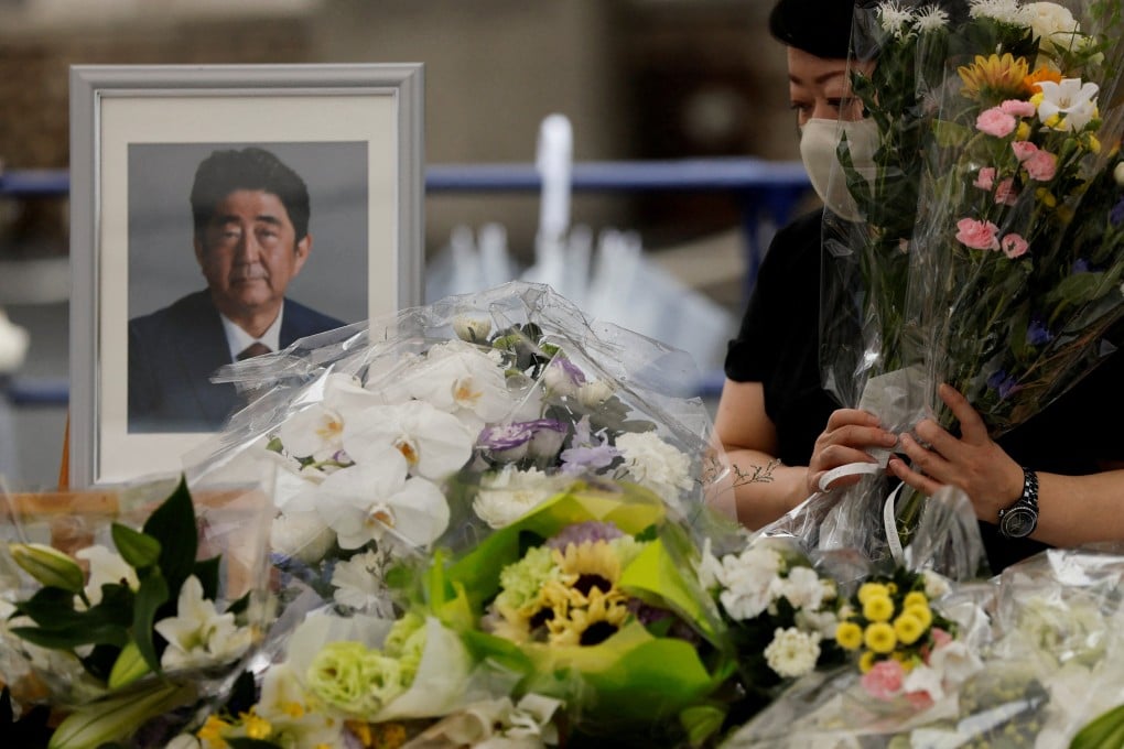 A mourner offers flowers next to a picture of late former Japanese Prime Minister Shinzo Abe, who was shot while campaigning for a parliamentary election, on the day to mark a week after his assassination at the Liberal Democratic Party headquarters, in Tokyo on July 15. Photo: Reuters