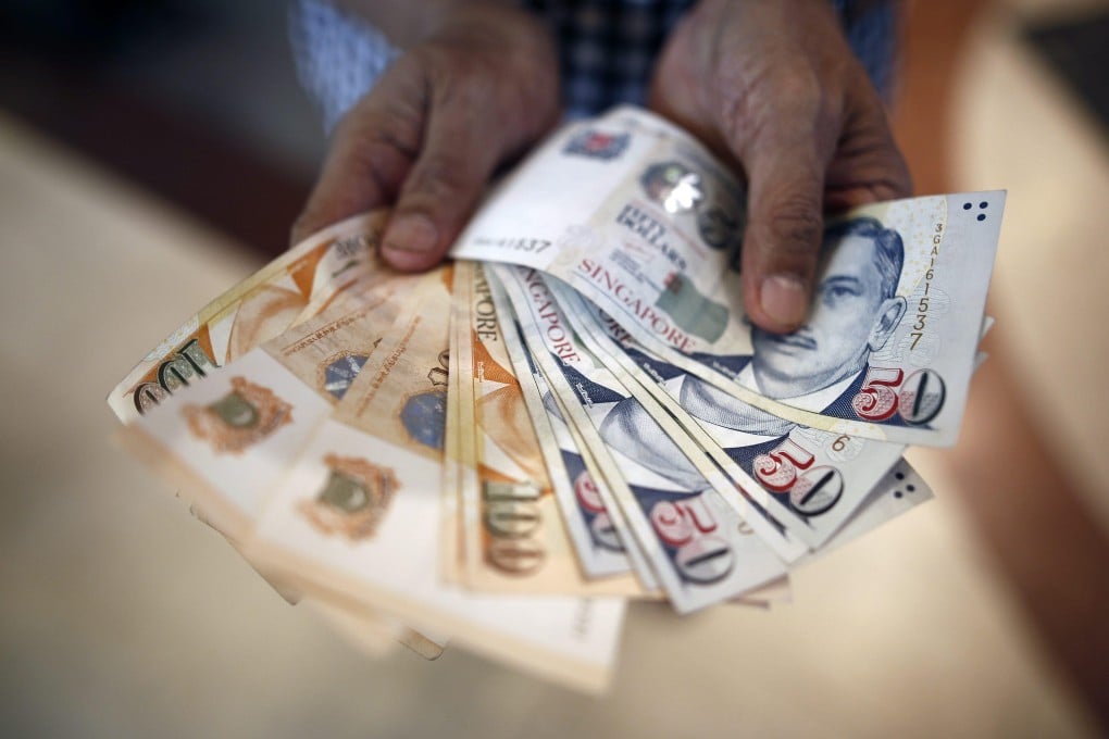 A customer queuing at a money changer shows his Singapore dollar banknotes. The city state has emerged as an outlier in a sea of ailing Asian currencies. Photo: EPA-EFE