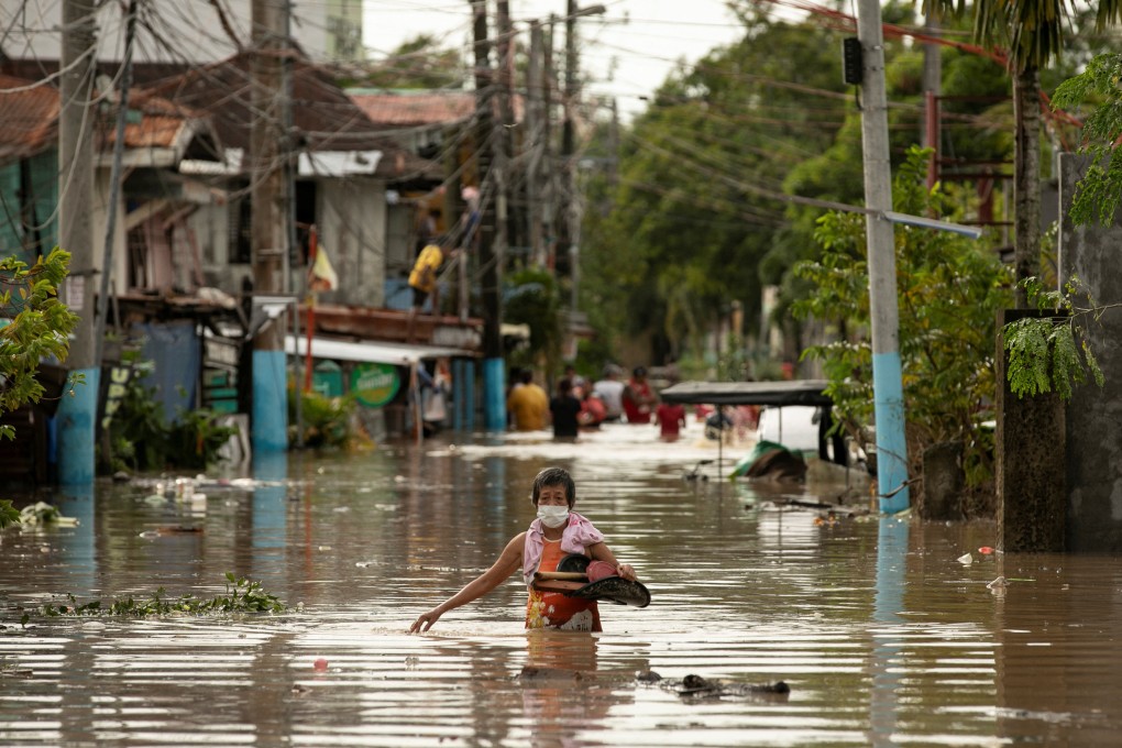 Residents wade through waist-deep floodwaters in Bulacan province on Monday after Typhoon Noru swept through. Photo: Reuters