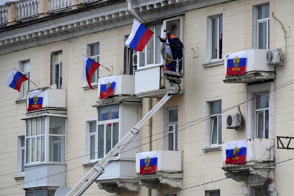 Workers hang Russian flags outside an apartment building in Luhansk, eastern Ukraine on Tuesday. Photo: AP