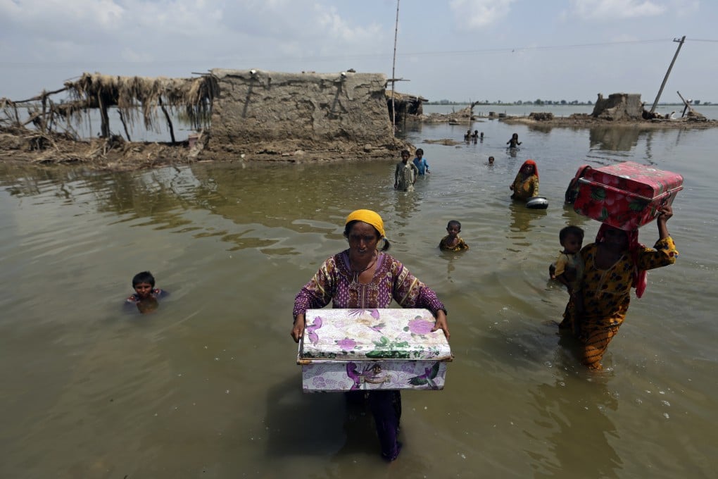 Women carry belongings salvaged from their flooded home following monsoon rains in the Qambar Shahdadkot district of Sindh province, in Pakistan, on September 6. Photo: AP