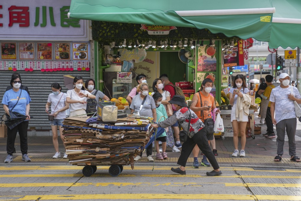 A cardboard collector passes by people waiting for a traffic light in Mong Kok on July 19. Photo: Sam Tsang