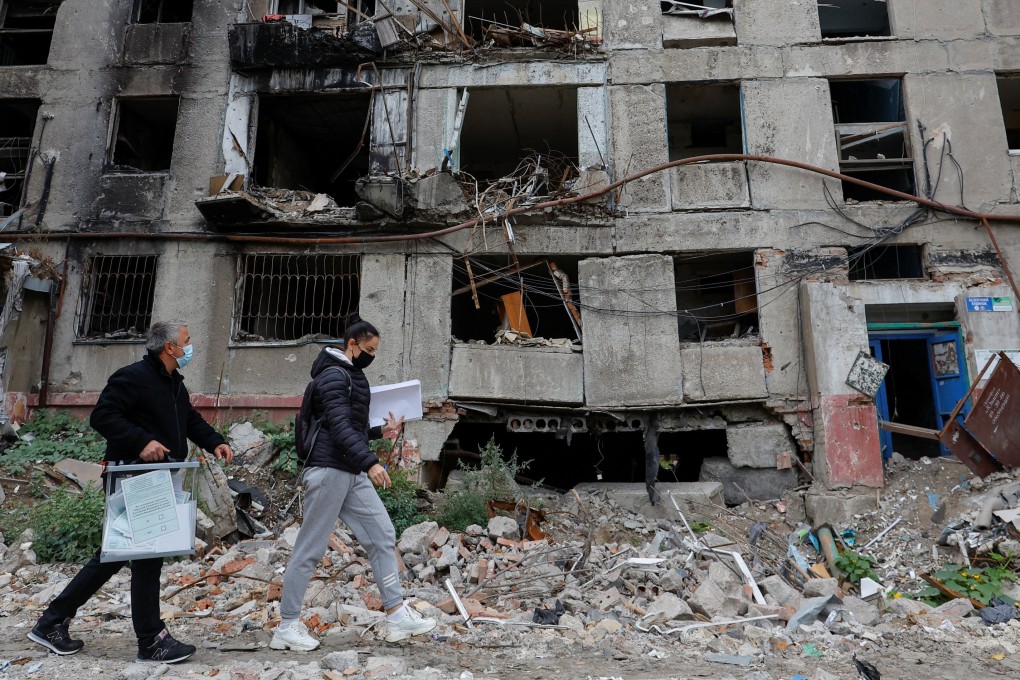 Members of an electoral commission walk past a destroyed building on September 24 in Mariupol, Ukraine, with a mobile ballot box on the second day of a referendum on the joining of the self-proclaimed Donetsk People’s Republic to Russia. Photo: Reuters