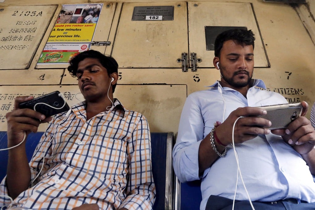 Commuters watch videos on their mobile phones as they travel in a suburban train in Mumbai, India. File photo: Reuters
