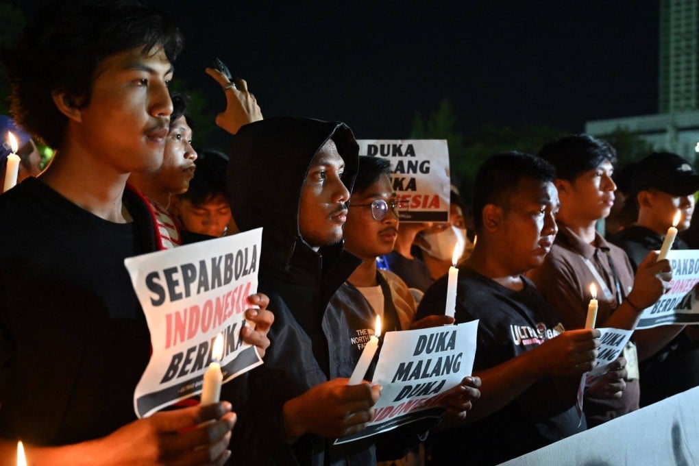 Indonesian football supporters pray during a candlelight vigil to show their condolences to victims of a stampede, in Jakarta on October 2, 2022. At least 127 people died at a football stadium in Indonesia when fans invaded the pitch and police responded with tear gas, triggering a stampede, authorities said. Photo: AFP