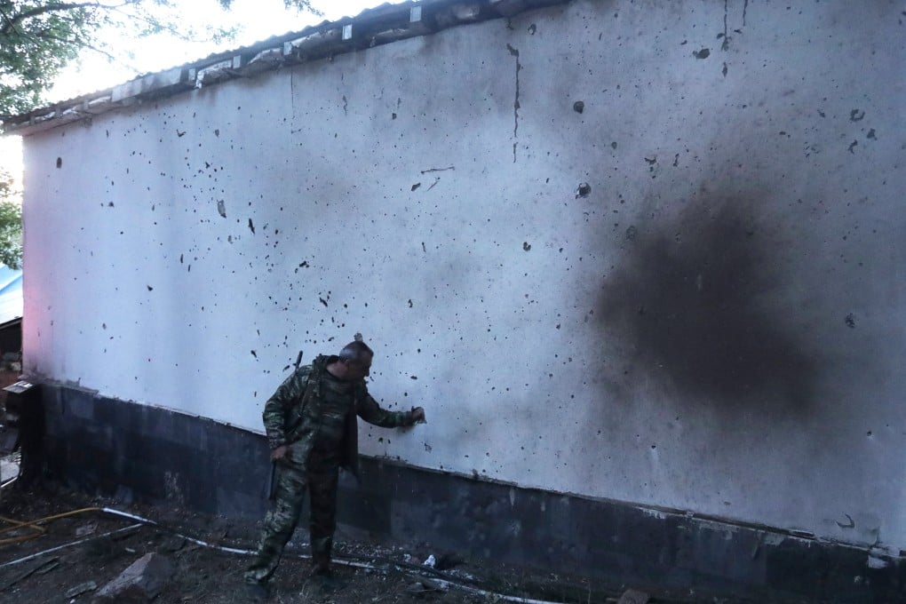 A man stands next to a building damaged by recent shelling during border clashes with Azerbaijan, in the town of Jermuk, Armenia. Photo: Photolure via Reuters