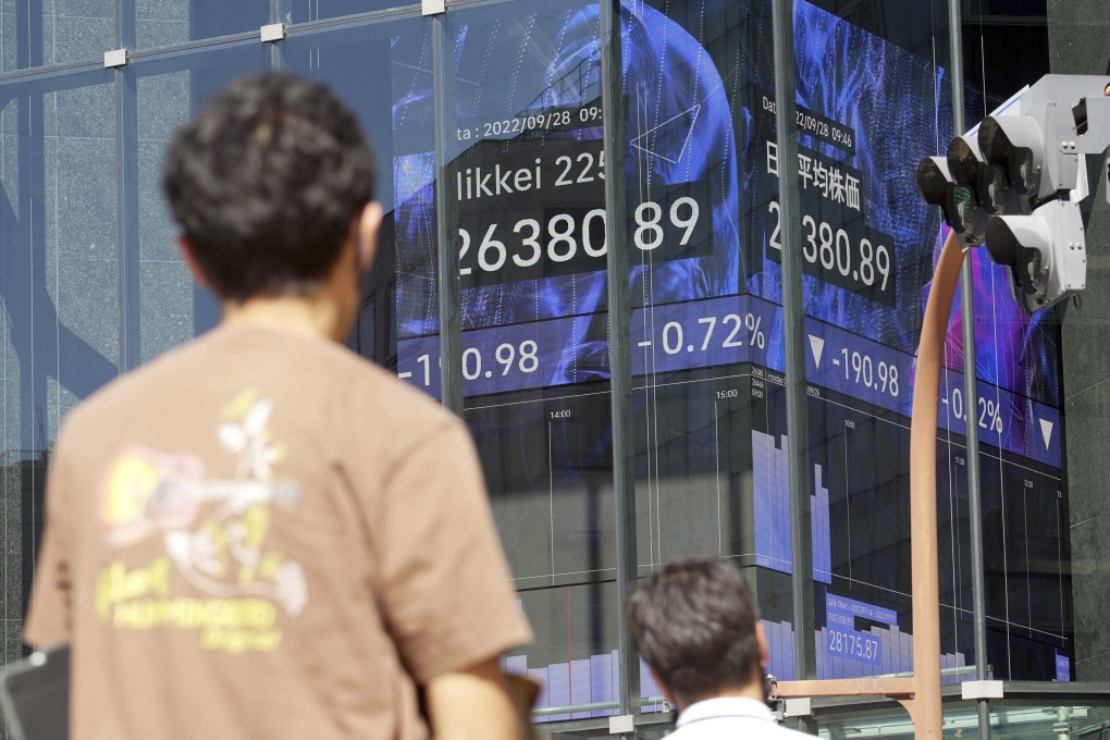 Pedestrians stand in front of an electronic board in Tokyo showing Japan’s Nikkei 225 index at a securities firm in September. Photo: AP