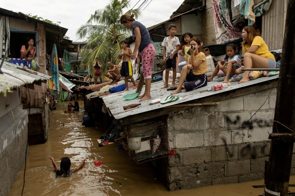 Residents wait on the roof for flooding to subside after Super Typhoon Noru in San Miguel, Bulacan province, Philippines, on September 26. Photo: Reuters
