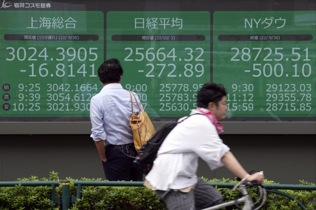 A person looks at an electronic stock board showing the Nikkei 225 and Dow indexes at a securities firm in Tokyo in October 2022. Photo: AP