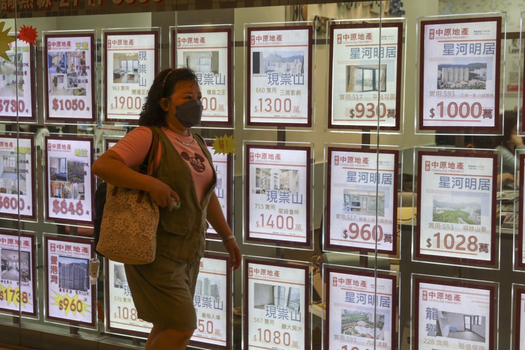 A woman walks past residential property advertisements displayed in the window of an estate agency in Wong Tai Sin on July 19, 2022. Photo: Edmond So