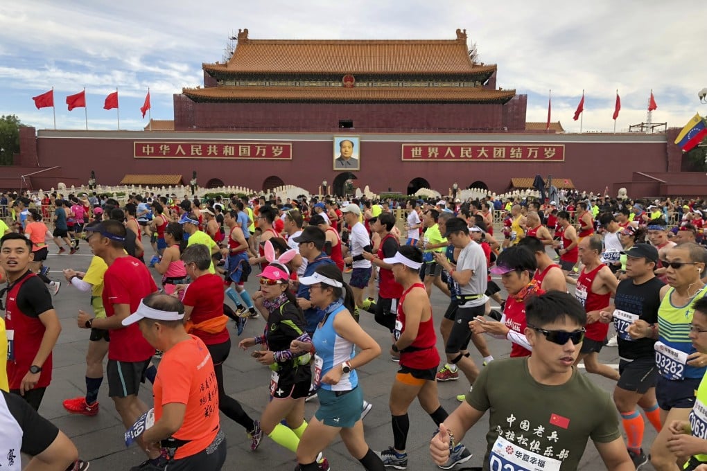 Runners pass near the large portrait of Chinese leader Mao Zedong on Tiananmen Gate near Tiananmen Square at the start of the Beijing Marathon on September 16, 2018. Photo: AP