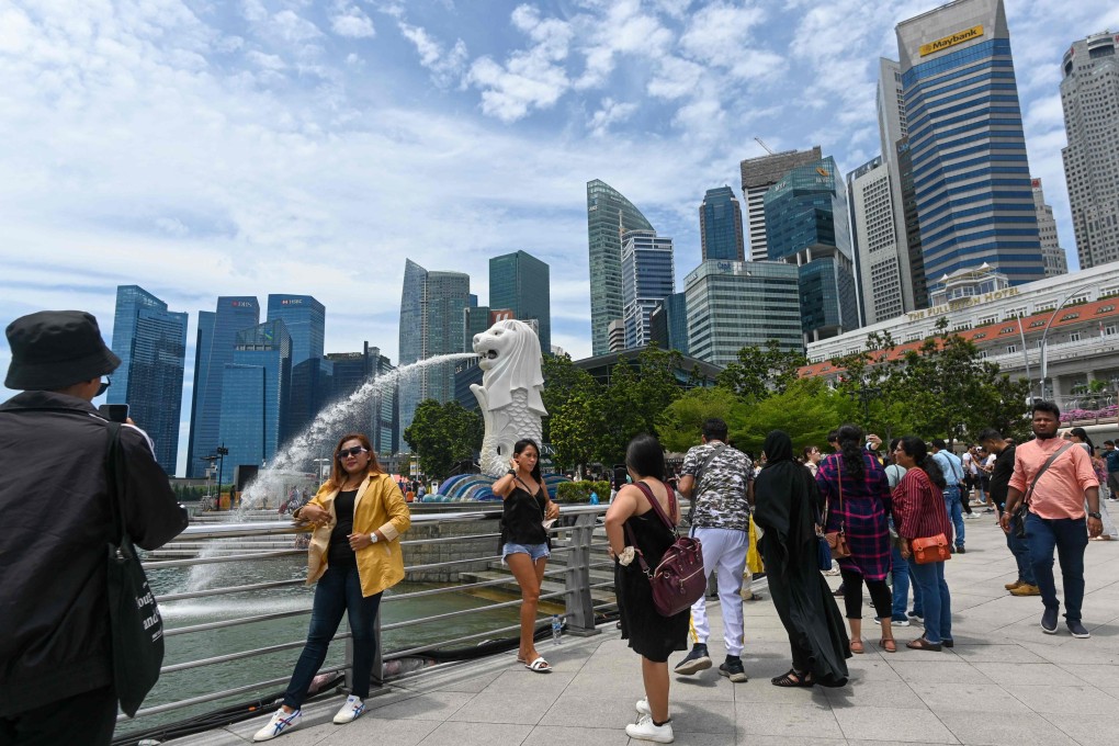 People pose with the Merlion statue along the Marina Bay waterfront in Singapore on September 23. Photo: AFP