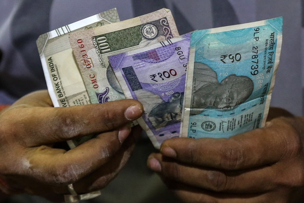 A vendor counts Indian rupee notes at a roadside shop in Mumbai. Photo: EPA-EFE