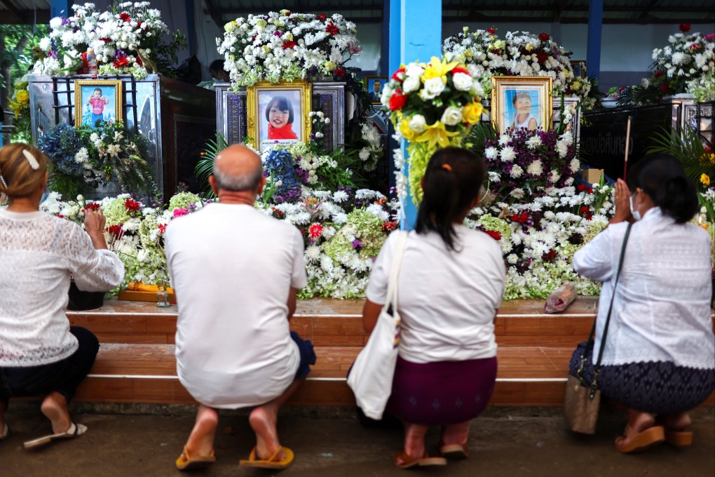 Families in Thailand pray following a mass shooting last week which claimed 36 lives, including children. Photo: Reuters