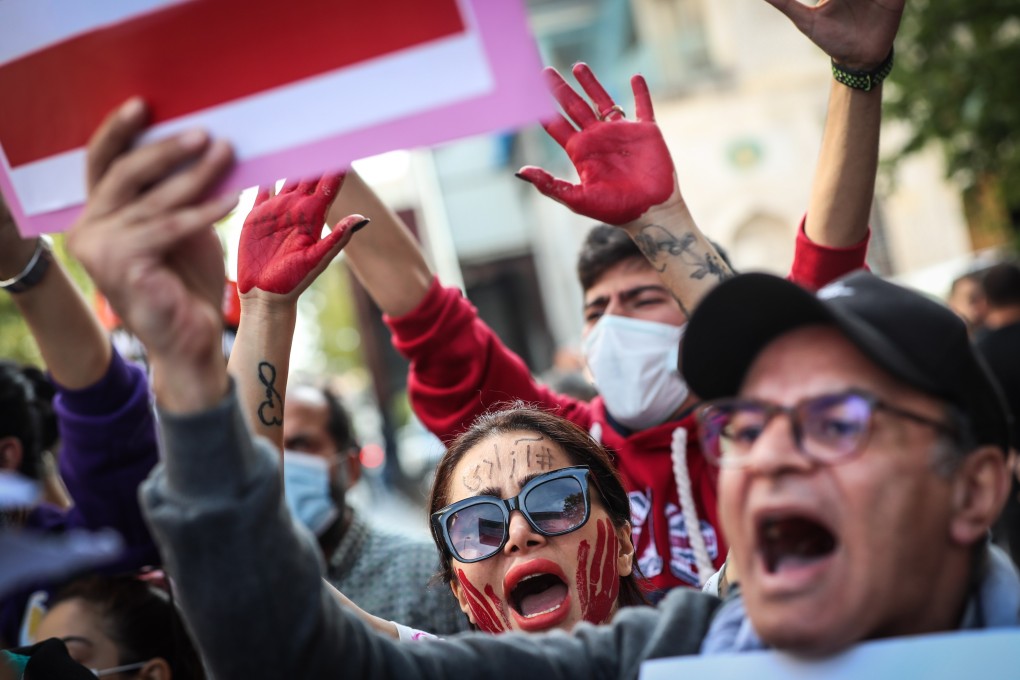 Iranian people hold pictures of Mahsa Amini with their hands painted in red during a protest outside the Iranian consulate in Istanbul on Tuesday. Photo: EPA-EFE