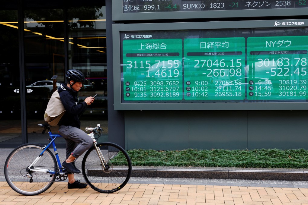 A cyclist stands in front of an electronic board showing Shanghai stock index and other market data on September 22. Photo: Reuters