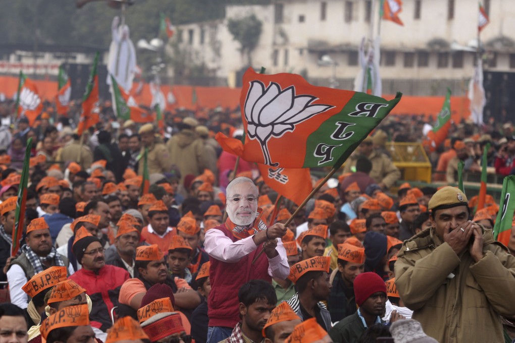 A man wearing a mask of Indian Prime Minister Narendra Modi waves a flag of his Hindu nationalist Bharatiya Janata Party during a rally in December 2019. Photo: AP