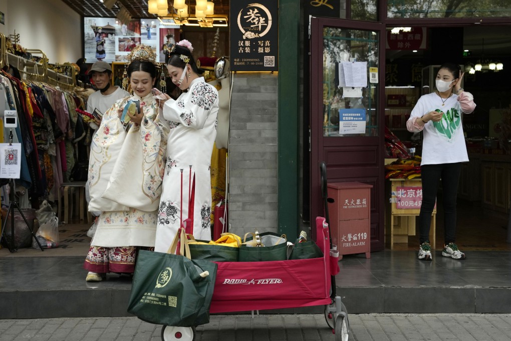 Women in traditional costume wait outside a photography shop catering to tourists in Beijing on September 29. Domestic-led growth should provide some forward momentum and the weak yuan will give exporters a competitive advantage. Photo: AP