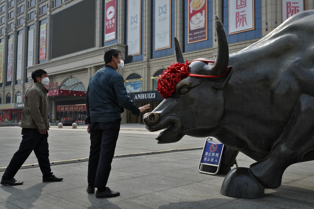 A man touches a bull statue outside a retail mall in Beijing in March 2020. Photo: AP