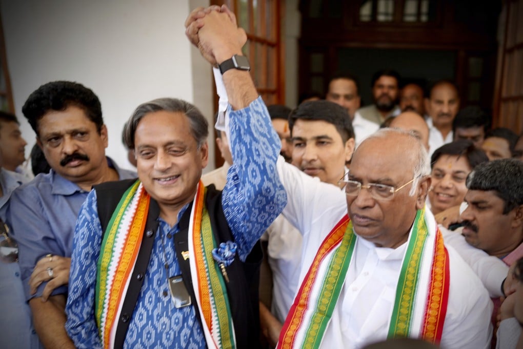 Newly elected Congress Party president Mallikarjun Kharge, right, raises hands with party leader Shashi Taroor. Photo: AFP
