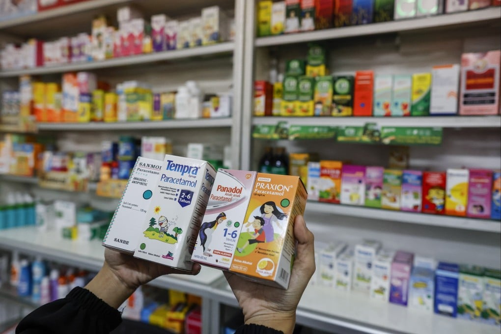 A shopkeeper holds boxes of liquid medicine at a drugstore in Jakarta, Indonesia, where deaths have been inked to some brands (not necessarily those pictured). Photo: EPA-EFE
