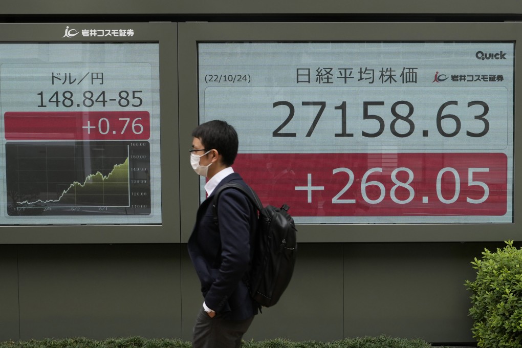 A man walks by monitors showing the Japanese yen’s exchange rate against the US dollar (left) and Japan’s Nikkei 225 index at a securities firm in Tokyo on Monday. Photo: AP