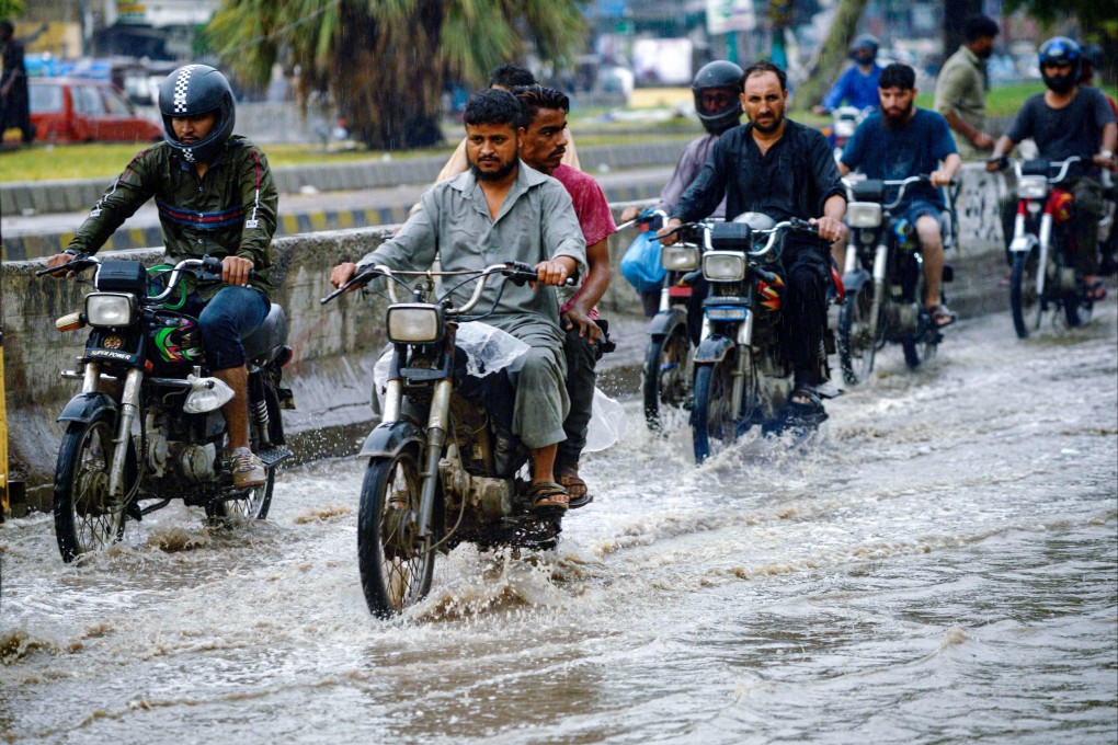 Motorcyclists make their way through a flooded street after heavy rains in Karachi on September 12. In climate-hit Pakistan, for example, the AIIB is part of a project to link up the megacity through a network of hybrid buses, partly run on biogas, to make commuting faster and safer. Photo: AFP