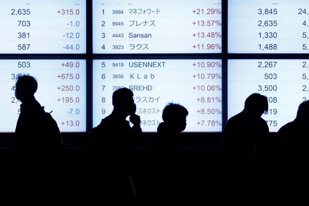 People are silhouetted as they walk past an electric stock quotation board outside a brokerage in Tokyo on October 18, 2022. Photo: Reuters